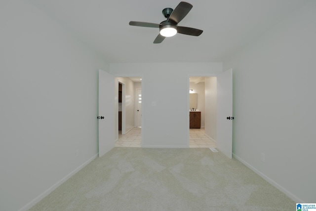 unfurnished bedroom featuring light carpet, ceiling fan, and ensuite bath