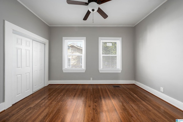 unfurnished bedroom with ceiling fan, a closet, dark hardwood / wood-style floors, and crown molding