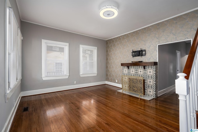 unfurnished living room with dark hardwood / wood-style floors, a tile fireplace, and ornamental molding