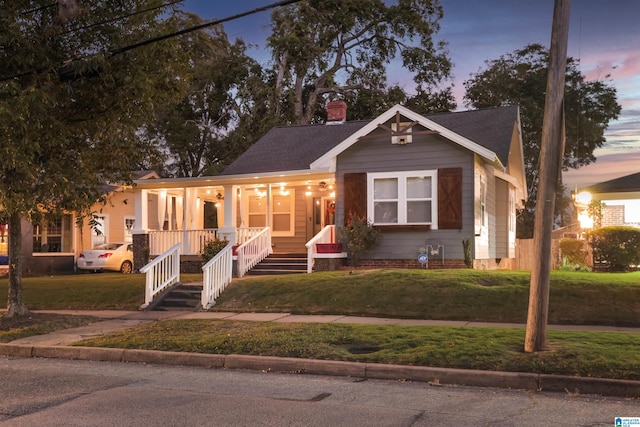 bungalow with covered porch and a yard