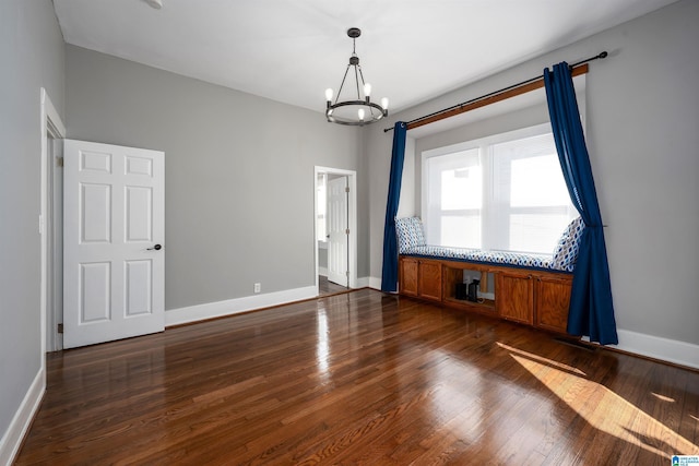 empty room with dark hardwood / wood-style floors and an inviting chandelier