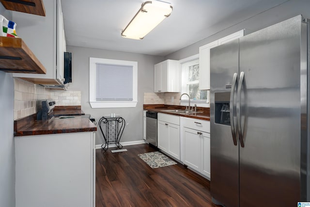 kitchen with stainless steel appliances, butcher block counters, white cabinetry, and sink