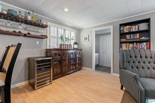 bar featuring light wood-type flooring, crown molding, and wine cooler