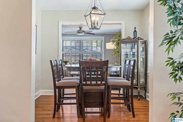 dining area featuring ceiling fan with notable chandelier and wood-type flooring