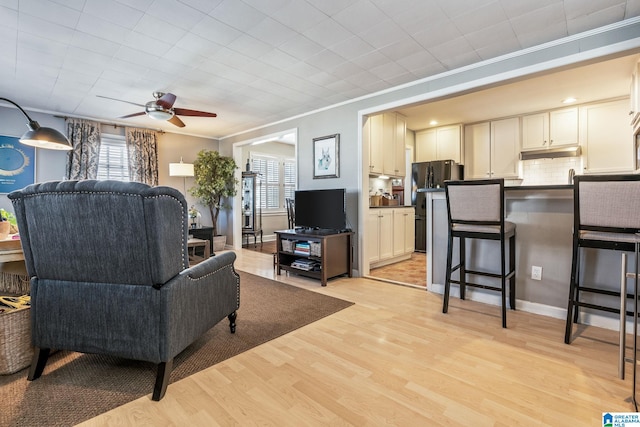 living room featuring ceiling fan, light hardwood / wood-style flooring, a healthy amount of sunlight, and crown molding