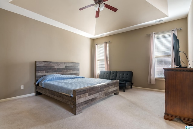 carpeted bedroom with a raised ceiling and ceiling fan