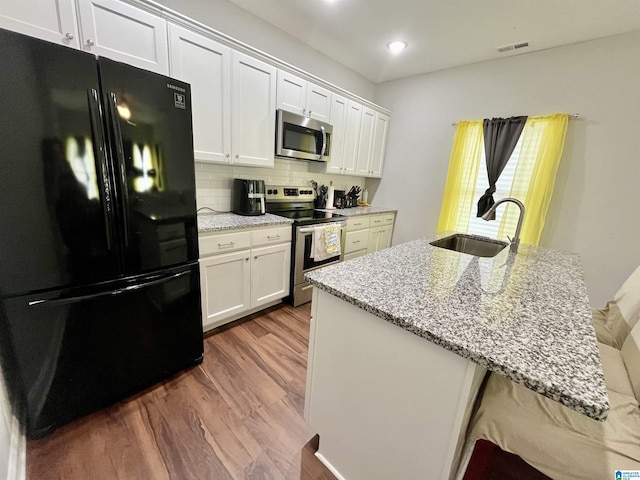 kitchen featuring white cabinets, appliances with stainless steel finishes, sink, and light stone counters