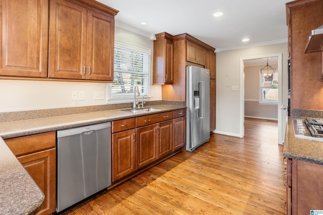 kitchen featuring appliances with stainless steel finishes, brown cabinets, a sink, and ornamental molding