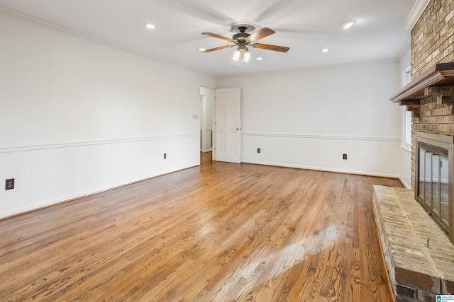 unfurnished living room with light wood-style floors, ceiling fan, a fireplace, and crown molding