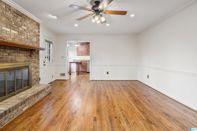 unfurnished living room featuring a brick fireplace, visible vents, baseboards, crown molding, and light wood-style floors