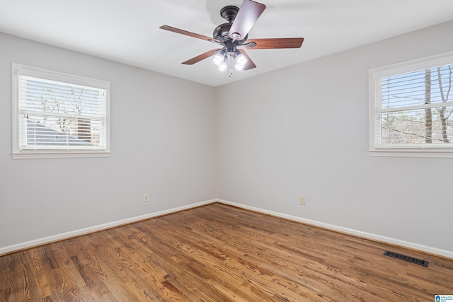 spare room with baseboards, visible vents, ceiling fan, and wood finished floors