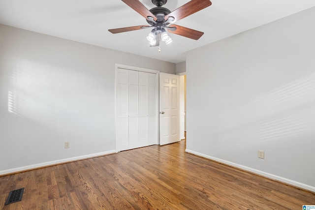 unfurnished bedroom with a closet, wood finished floors, visible vents, and baseboards