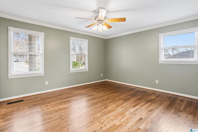 unfurnished room with ceiling fan, wood finished floors, visible vents, baseboards, and ornamental molding