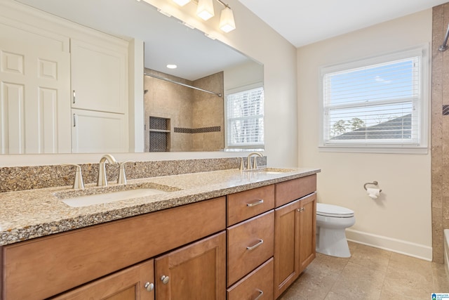 full bathroom featuring a sink, a tile shower, and baseboards