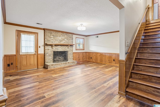 unfurnished living room with a wealth of natural light, visible vents, a textured ceiling, and wainscoting