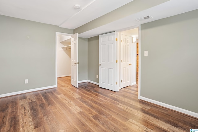 unfurnished bedroom featuring visible vents, baseboards, and wood finished floors