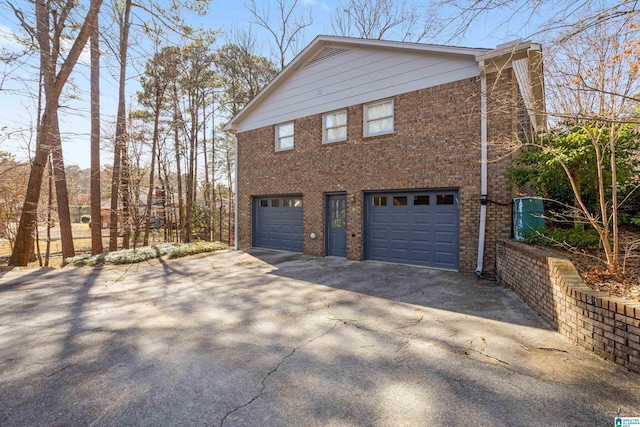 view of home's exterior with a garage, aphalt driveway, and brick siding