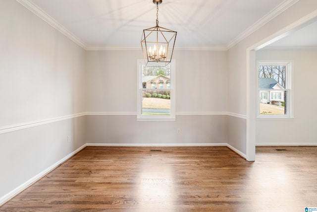 spare room with an inviting chandelier, baseboards, ornamental molding, and wood finished floors