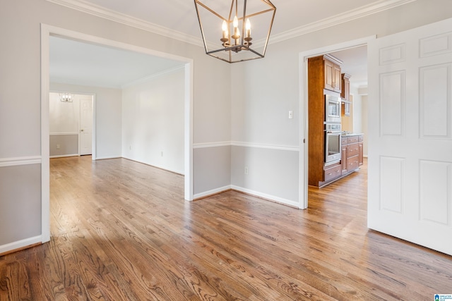 empty room with a chandelier, wood finished floors, and crown molding