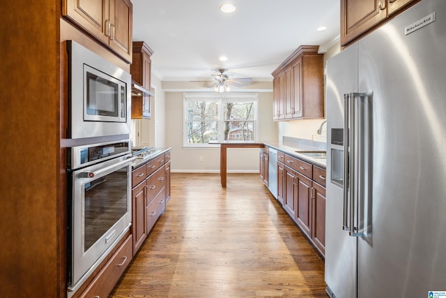 kitchen with stainless steel appliances, light wood-type flooring, light countertops, and brown cabinets