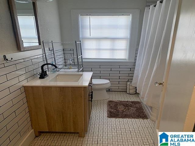 bathroom featuring toilet, vanity, tile walls, and tile patterned floors