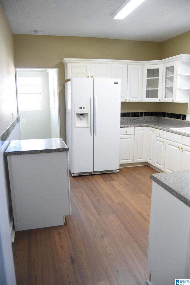 kitchen featuring dark hardwood / wood-style flooring, white refrigerator with ice dispenser, and white cabinets