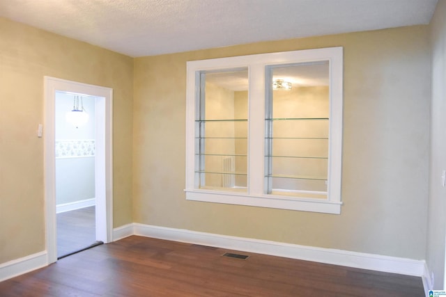 spare room with a textured ceiling and dark hardwood / wood-style flooring