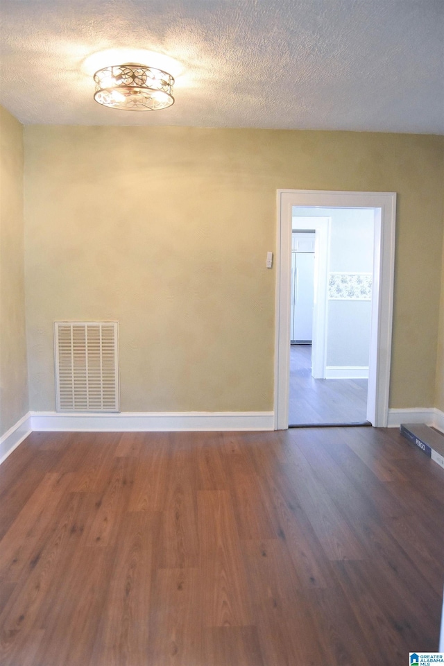 empty room with a textured ceiling and dark hardwood / wood-style flooring