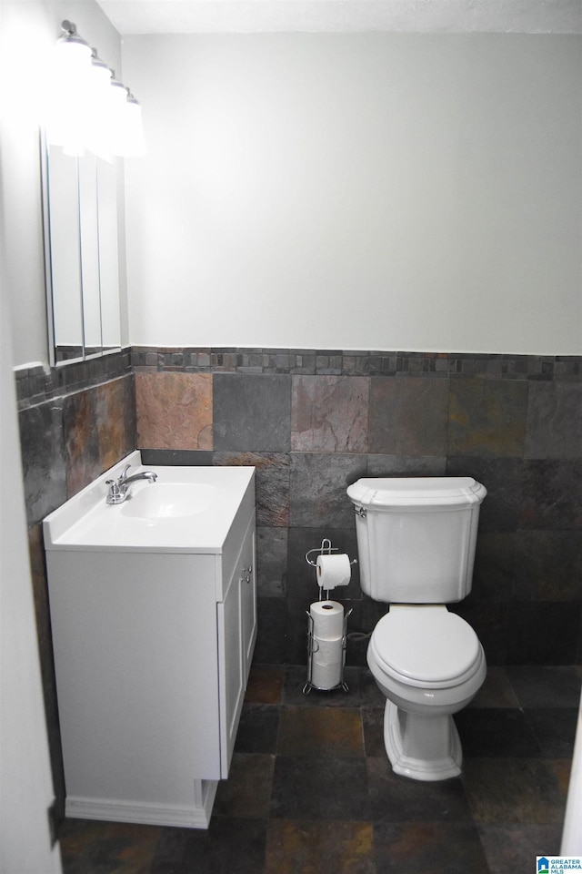 bathroom with toilet, tile walls, and vanity