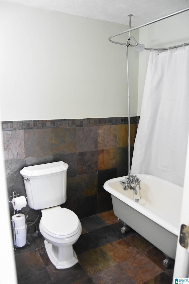 bathroom with toilet, tile walls, and a bathtub