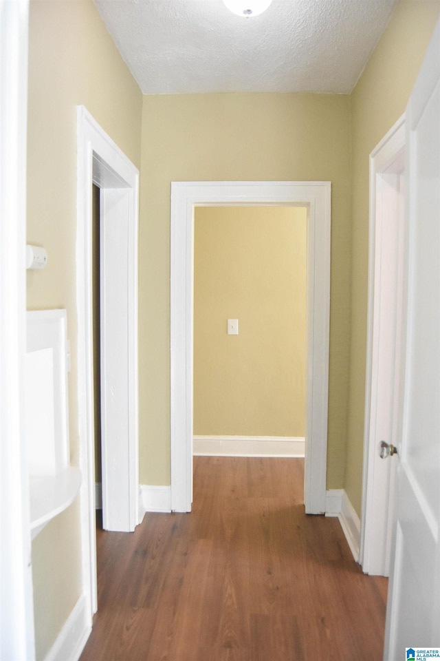 hall with dark hardwood / wood-style flooring and a textured ceiling