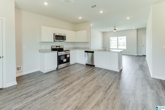 kitchen with ceiling fan, kitchen peninsula, white cabinetry, light hardwood / wood-style flooring, and stainless steel appliances