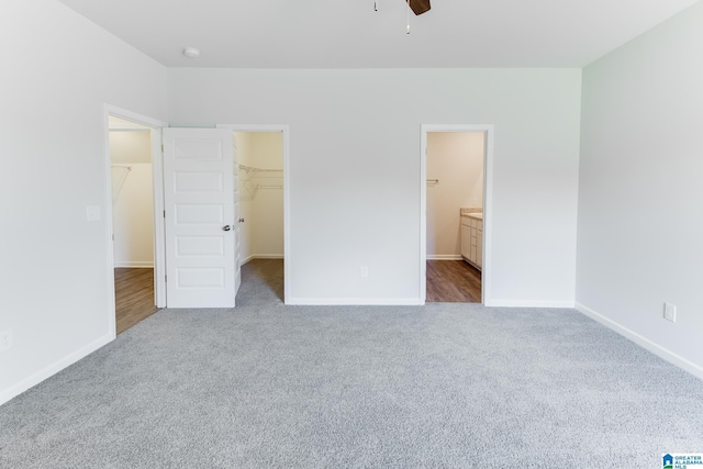 unfurnished bedroom with ceiling fan, carpet flooring, ensuite bath, a closet, and a walk in closet