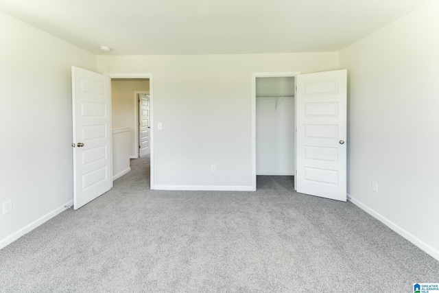 unfurnished bedroom with light colored carpet and a closet