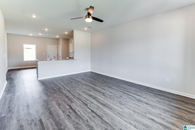 unfurnished living room with ceiling fan, dark hardwood / wood-style flooring, and sink