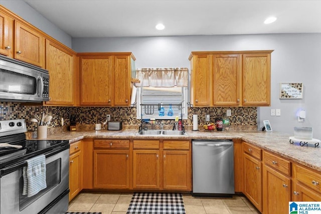 kitchen with light tile patterned floors, decorative backsplash, sink, stainless steel appliances, and light stone counters