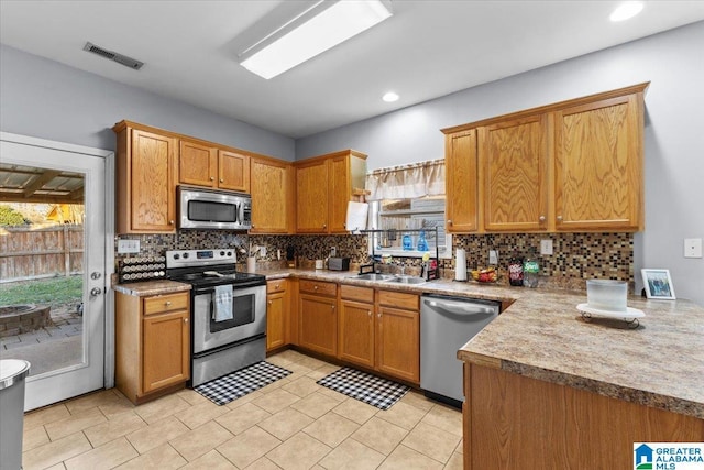 kitchen with decorative backsplash, sink, light tile patterned floors, and stainless steel appliances