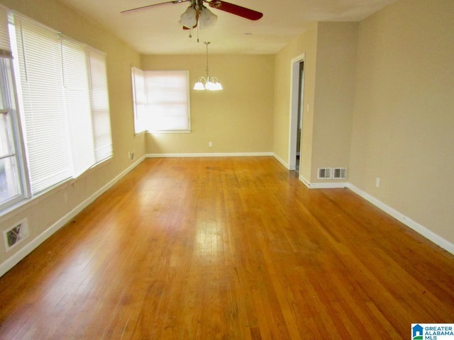 unfurnished room featuring light wood-type flooring and ceiling fan with notable chandelier