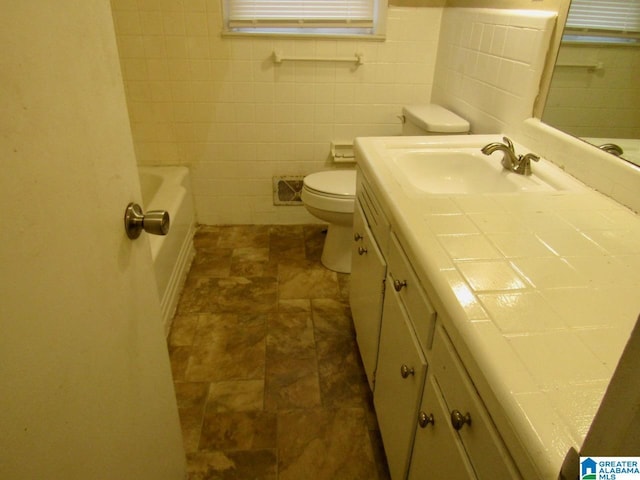 bathroom featuring toilet, vanity, tile walls, and a bathtub