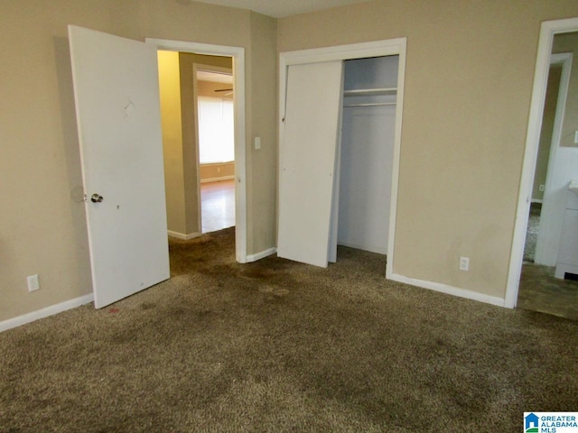 unfurnished bedroom with dark colored carpet and a closet