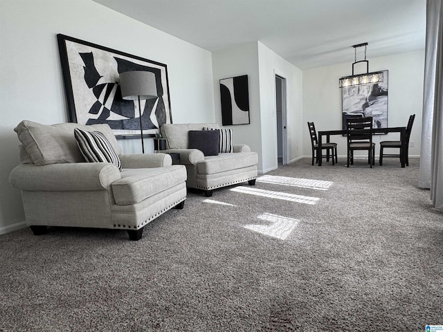 living room featuring a notable chandelier, carpet floors, and baseboards