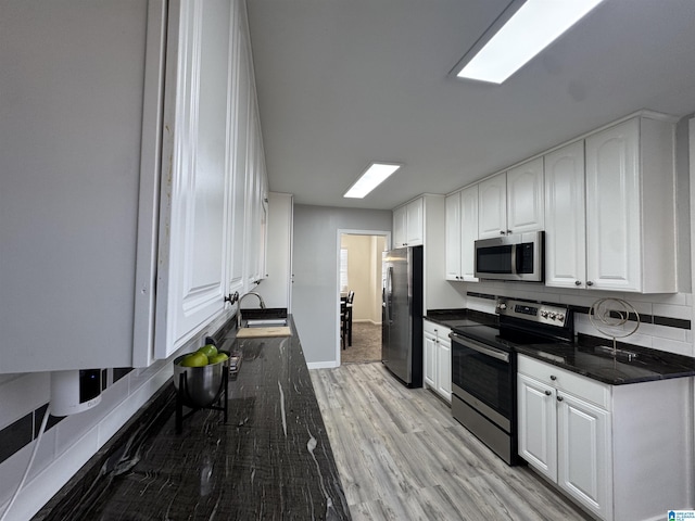 kitchen featuring stainless steel appliances, decorative backsplash, light wood-type flooring, white cabinets, and sink