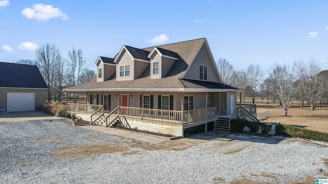 view of front of property with covered porch, a garage, and an outbuilding