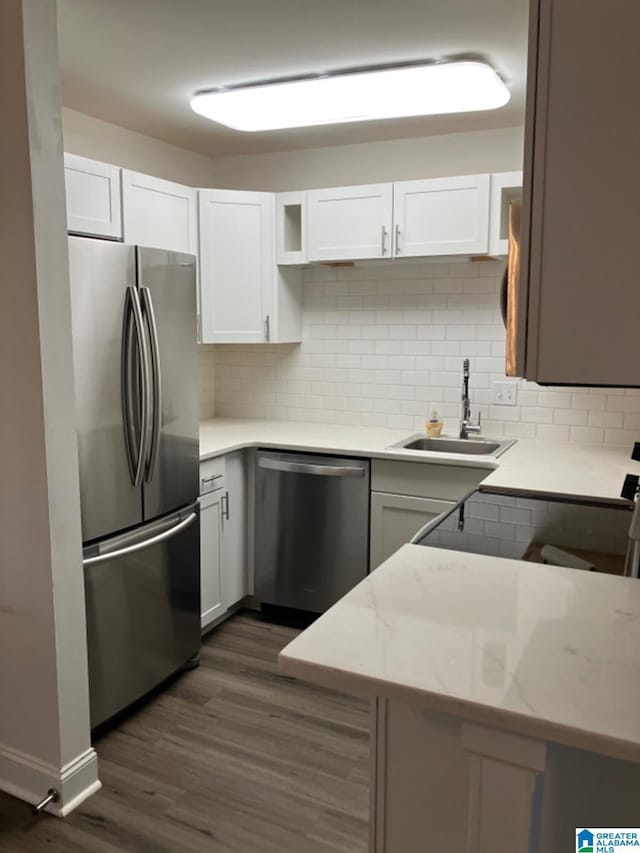 kitchen with white cabinetry, appliances with stainless steel finishes, backsplash, light stone countertops, and sink