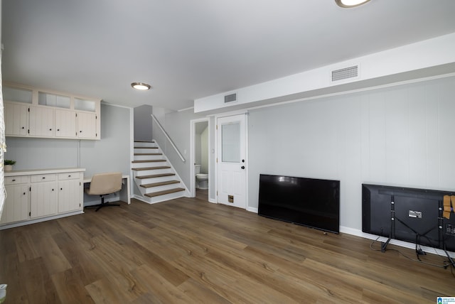 basement with built in desk and dark wood-type flooring