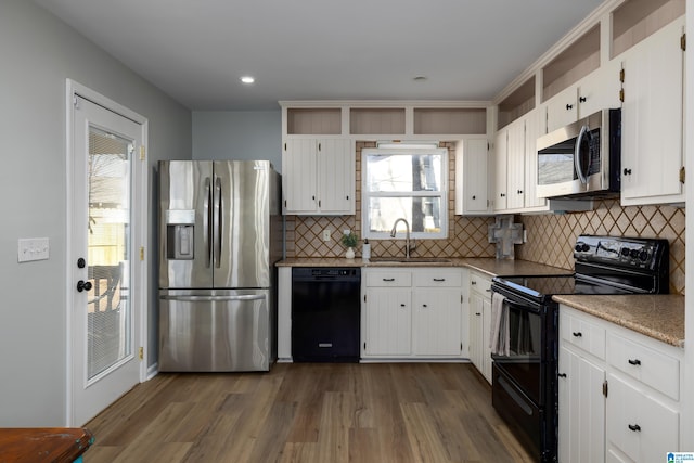 kitchen with dark hardwood / wood-style floors, tasteful backsplash, black appliances, white cabinets, and sink