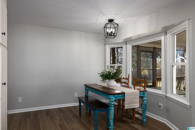 dining space with dark wood-type flooring, a wealth of natural light, and an inviting chandelier