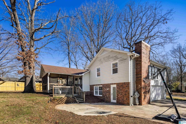 rear view of property featuring a garage, a sunroom, and a yard