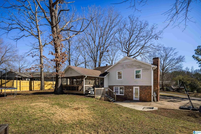 back of property featuring a trampoline, a patio area, a sunroom, and a yard