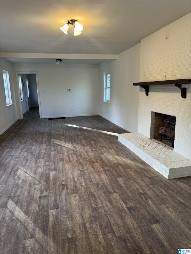 unfurnished living room with dark wood-type flooring and a brick fireplace